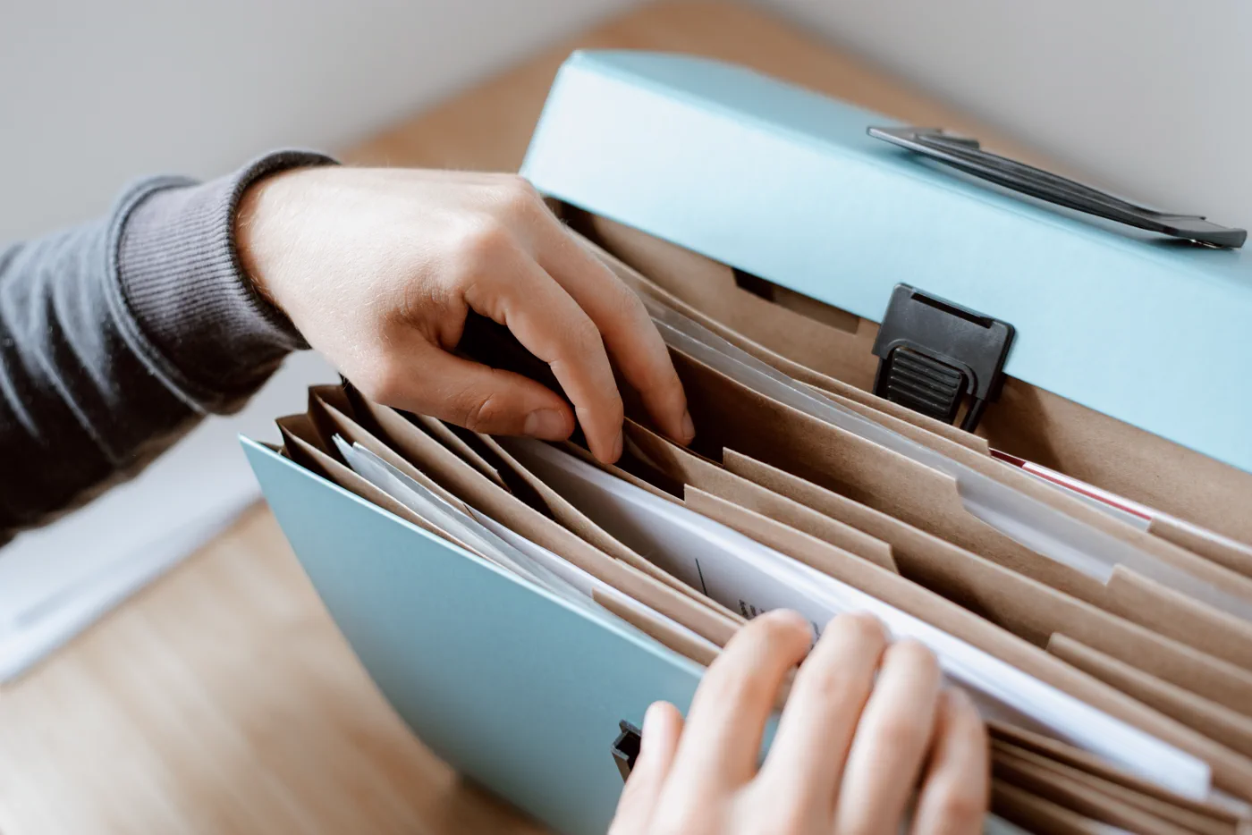 Hands organizing documents in an expanding file folder