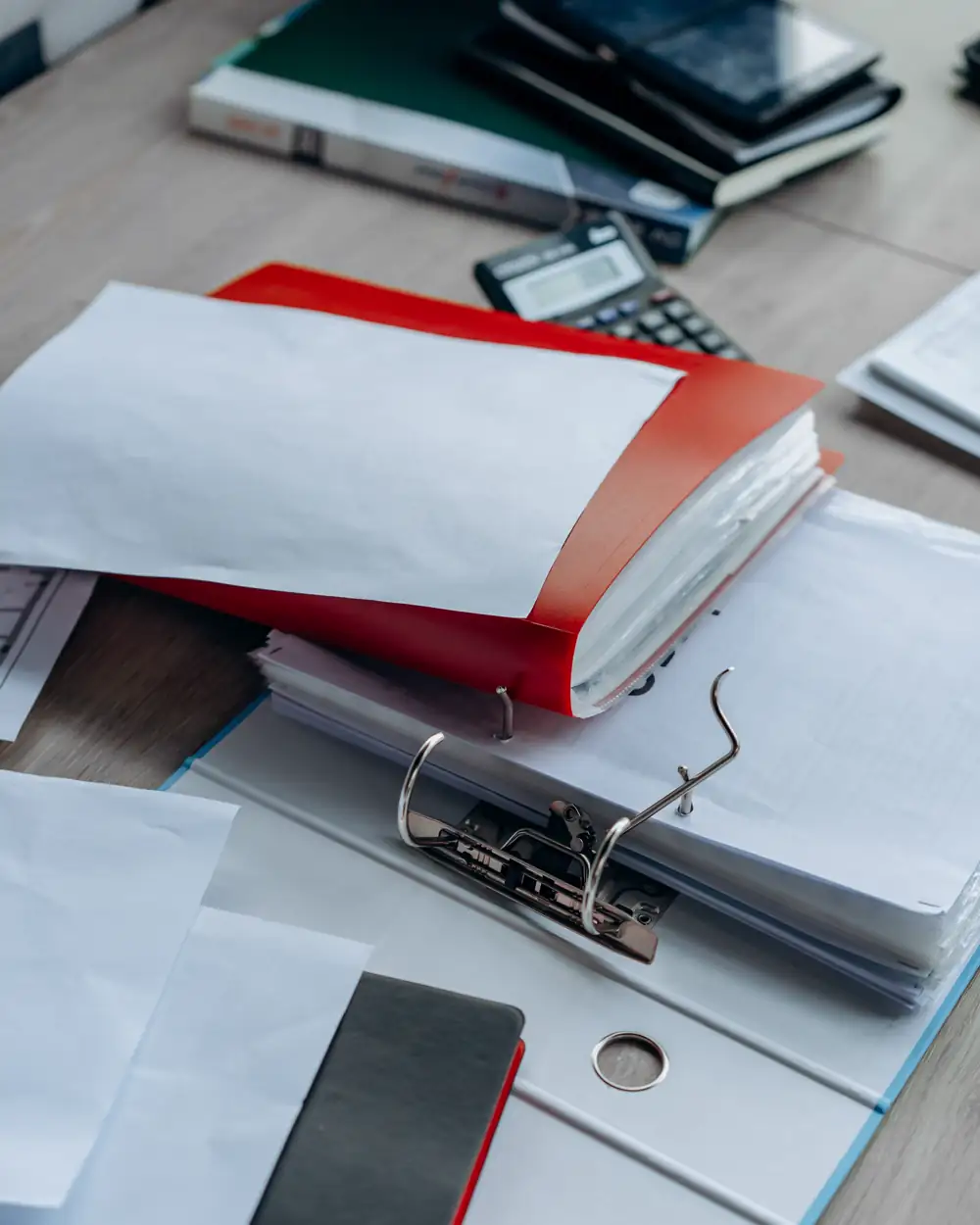 Office binders and paperwork arranged on a desk beside a calculator