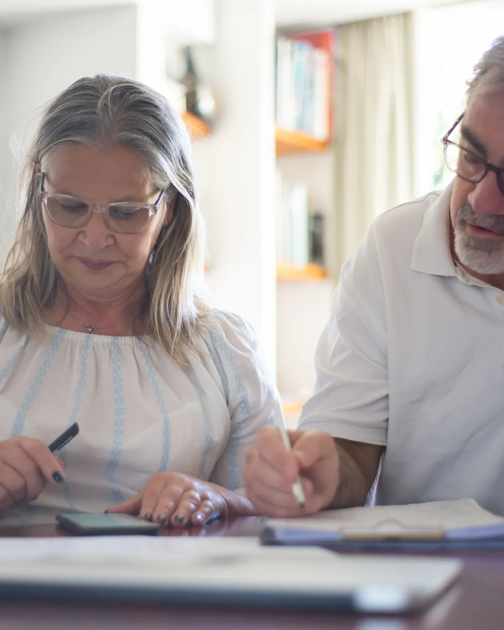 Mature couple organizing household financial documents at a table